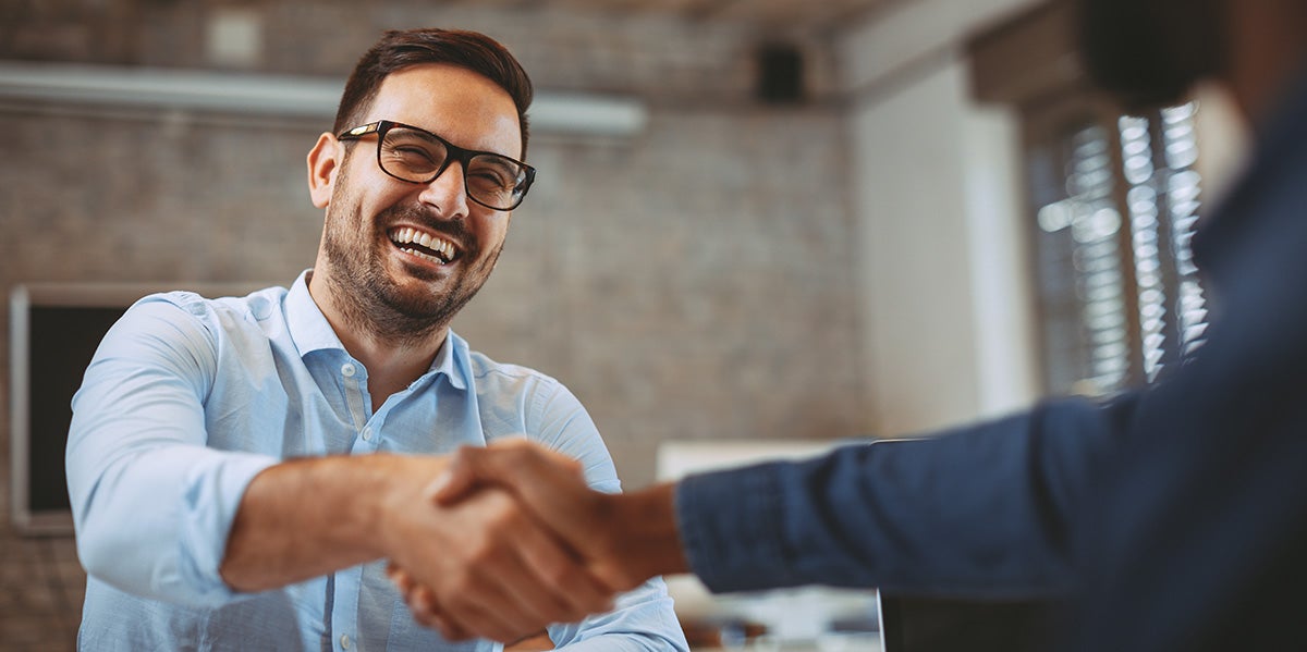 A car salesperson shaking hands with a customer in a dealership