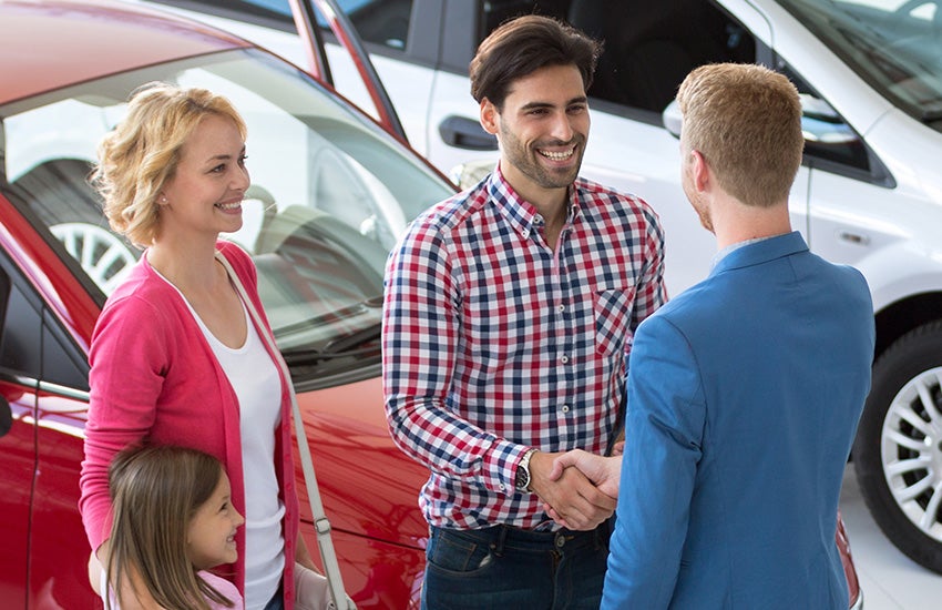 Automotive technician shaking hands with a family, symbolizing trust and quality service.
